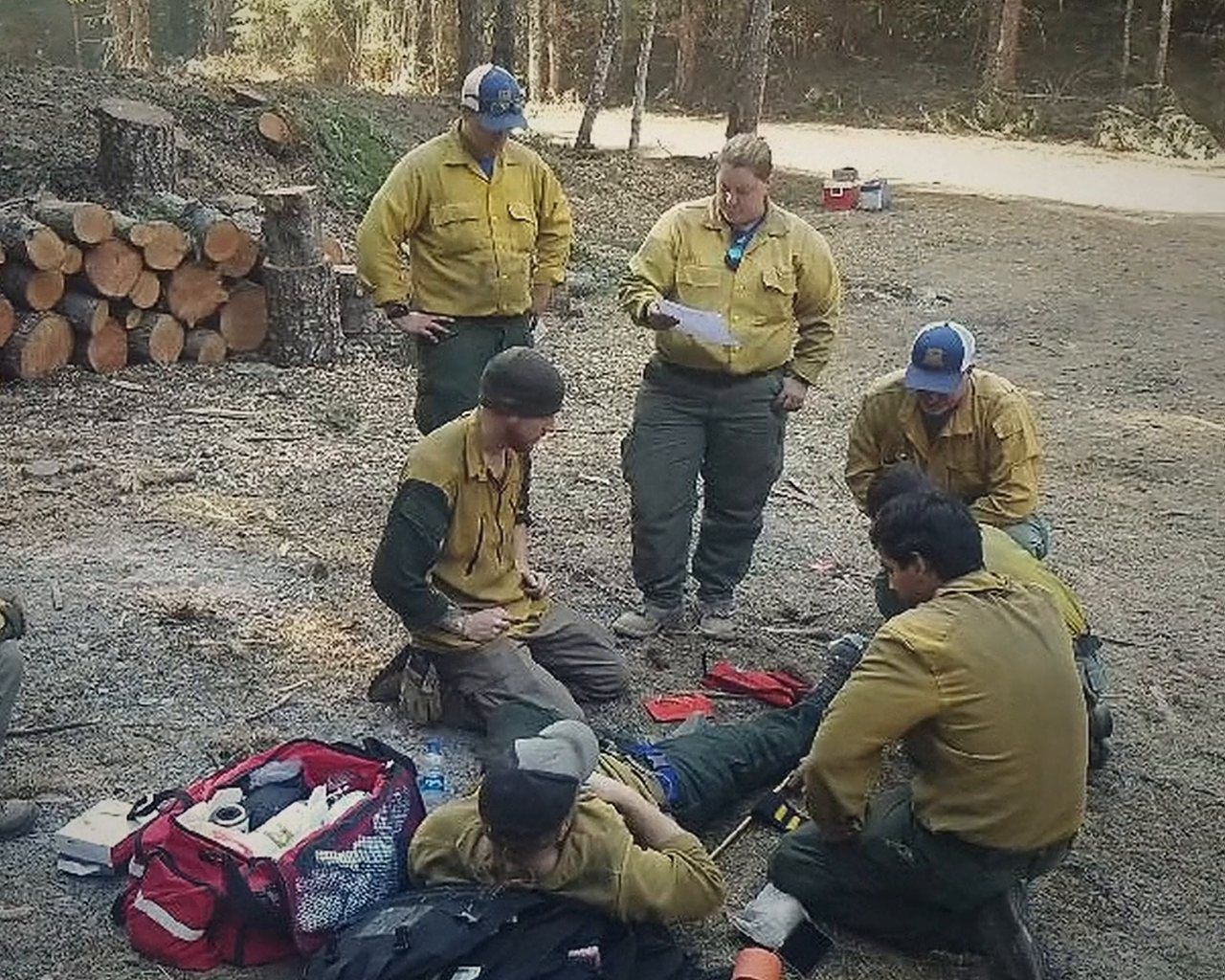 A crew kneeling around a patient on the ground with a medical bag